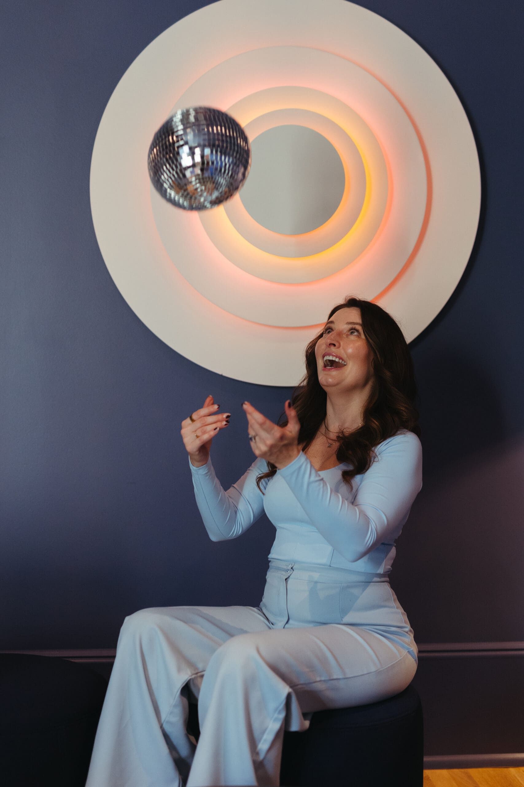 Woman sitting throwing a disco ball in the air